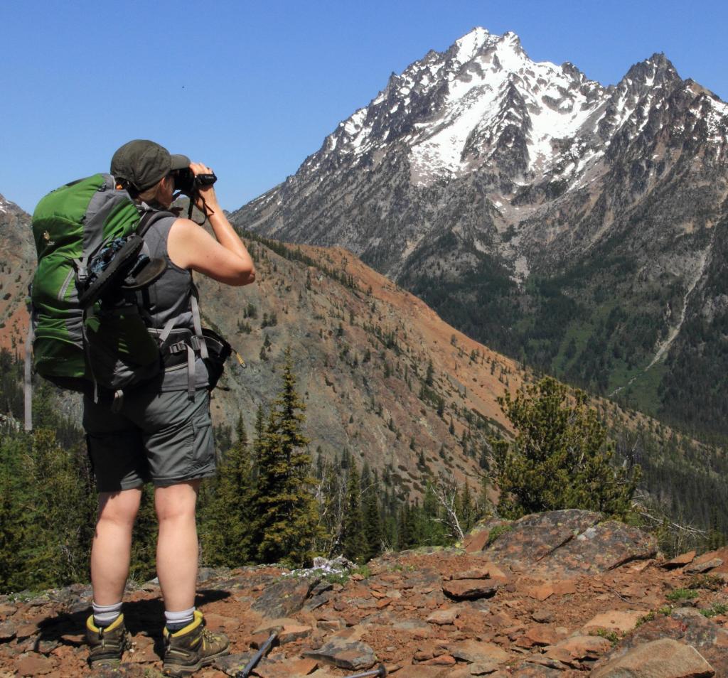 Female hiker leaning on boulders with hiking poles and backpack